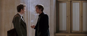 Movie still from “Stay” (2005), directed by Marc Forster – A man smoking a cigarette while talking to another man in a suit; Medium shot, Over the shoulder angle