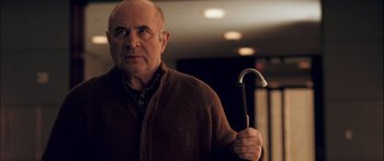 Movie still from “Stay” (2005), directed by Marc Forster – An older man holding an umbrella while wearing a sweater; Medium shot, Low angle