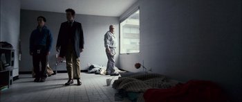 Movie still from “Stay” (2005), directed by Marc Forster – Two men standing in an empty room next to blankets; Wide shot, Low angle