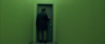Movie still from “Stay” (2005), directed by Marc Forster – A man standing in front of an open green door; Wide shot, Over the shoulder angle