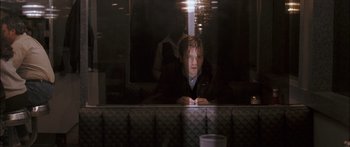 Movie still from “Stay” (2005), directed by Marc Forster – A man sitting at a table looking at his cell phone; Medium shot, Over the shoulder angle