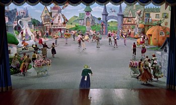 Movie still from “Babes in Toyland” (1961), directed by Jack Donohue – A group of people standing in front of a stage; Extreme Wide shot, High angle