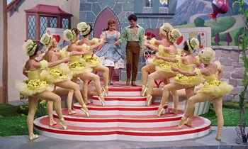 Movie still from “Babes in Toyland” (1961), directed by Jack Donohue – A group of people dressed in costumes on a stage; Wide shot, High angle