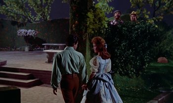 Movie still from “Babes in Toyland” (1961), directed by Jack Donohue – A man and a woman holding hands in front of a tree; Wide shot, Over the shoulder angle