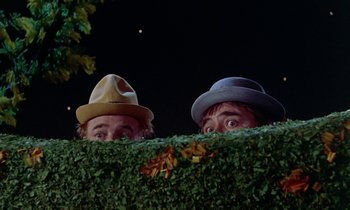 Movie still from “Babes in Toyland” (1961), directed by Jack Donohue – Two men in hats are peeking over a hedge; Close Up shot, Low angle