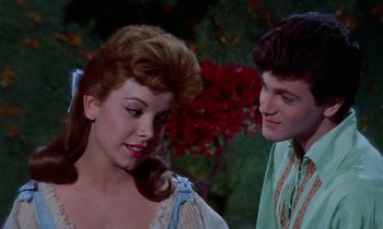 Movie still from “Babes in Toyland” (1961), directed by Jack Donohue – A young woman and a young man standing next to each other in front of a bush; Close Up shot, Over the shoulder angle