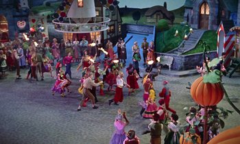 Movie still from “Babes in Toyland” (1961), directed by Jack Donohue – A group of people dressed in costumes dancing in the street; Extreme Wide shot, High angle