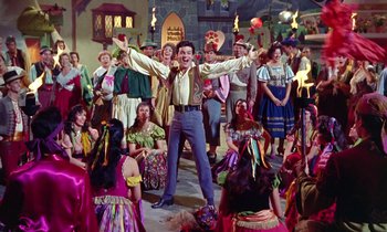 Movie still from “Babes in Toyland” (1961), directed by Jack Donohue – A group of people dressed up in costumes and singing; Wide shot, High angle