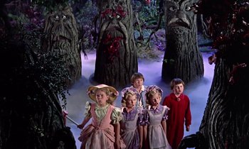 Movie still from “Babes in Toyland” (1961), directed by Jack Donohue – A group of children dressed in costumes standing in front of trees; Wide shot, Low angle