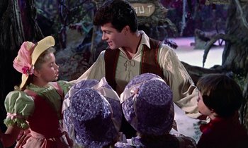 Movie still from “Babes in Toyland” (1961), directed by Jack Donohue – A man in a brown shirt is holding a purple hat; Medium shot, Over the shoulder angle