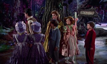 Movie still from “Babes in Toyland” (1961), directed by Jack Donohue – A group of people standing next to each other in front of trees; Wide shot, Low angle