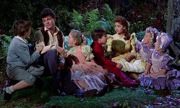 Movie still from “Babes in Toyland” (1961), directed by Jack Donohue – A group of people sitting on the grass; Medium shot, High angle