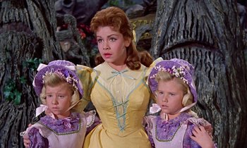 Movie still from “Babes in Toyland” (1961), directed by Jack Donohue – A woman and two little girls dressed in costumes; Medium shot, Low angle