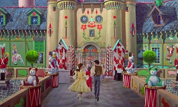 Movie still from “Babes in Toyland” (1961), directed by Jack Donohue – Two people are walking down a street in front of a castle; Extreme Wide shot, Low angle