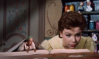 Movie still from “Babes in Toyland” (1961), directed by Jack Donohue – A woman and a man are looking at a book; Medium shot, Low angle