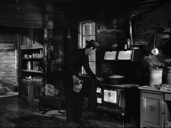 Movie still from “Baby Doll” (1956), directed by Elia Kazan – An old man standing in front of an old fashioned stove; Wide shot, High angle