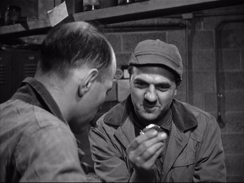 Movie still from “Baby Doll” (1956), directed by Elia Kazan – Two men are talking and one of them is eating a donut; Medium shot, High angle