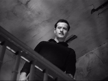 Movie still from “Baby Doll” (1956), directed by Elia Kazan – A black and white photo of a man standing at the top of a stair railing; Medium shot, Low angle