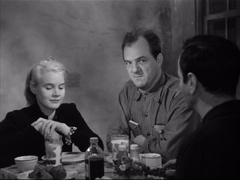Movie still from “Baby Doll” (1956), directed by Elia Kazan – Three people sitting at a dinner table with candles; Medium shot, Over the shoulder angle
