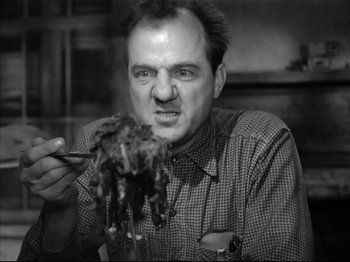 Movie still from “Baby Doll” (1956), directed by Elia Kazan – A black and white photo of a man eating a piece of food; Close Up shot, Low angle