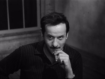 Movie still from “Baby Doll” (1956), directed by Elia Kazan – A black and white photo of a man smoking a cigarette; Close Up shot, High angle