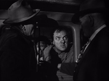 Movie still from “Baby Doll” (1956), directed by Elia Kazan – A black - and - white photo of a man in a train; Medium shot, Low angle