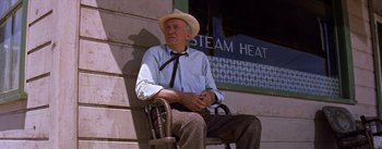 Movie still from “Bad Day at Black Rock” (1955), directed by John Sturges – An older man sitting on a chair outside a building; Medium shot, Low angle