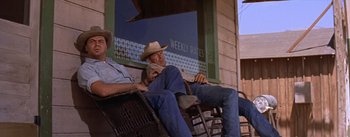 Movie still from “Bad Day at Black Rock” (1955), directed by John Sturges – Two men sitting on a chair in front of a building; Medium shot, Low angle
