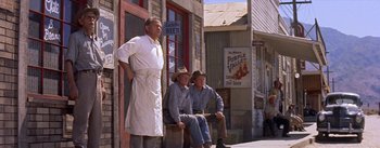 Movie still from “Bad Day at Black Rock” (1955), directed by John Sturges – A group of men sitting on top of a wooden bench; Wide shot, Low angle