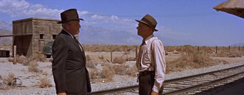 Movie still from “Bad Day at Black Rock” (1955), directed by John Sturges – Two men standing next to each other near a train track; Medium shot, Over the shoulder angle