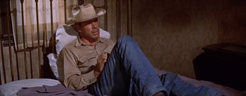 Movie still from “Bad Day at Black Rock” (1955), directed by John Sturges – A man wearing a cowboy hat sitting on the ground; Medium shot, High angle