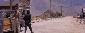 Movie still from “Bad Day at Black Rock” (1955), directed by John Sturges – A man walking down a street in a suit and hat; Extreme Wide shot, Low angle
