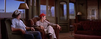 Movie still from “Bad Day at Black Rock” (1955), directed by John Sturges – A man sitting on a chair in a living room; Wide shot, Over the shoulder angle