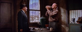 Movie still from “Bad Day at Black Rock” (1955), directed by John Sturges – Two men are having a drink at a table; Medium shot, Low angle