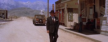 Movie still from “Bad Day at Black Rock” (1955), directed by John Sturges – An older man wearing a suit and hat walking down the street; Wide shot, Low angle