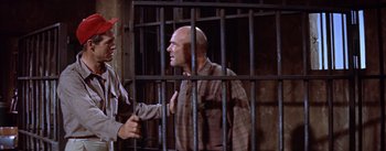 Movie still from “Bad Day at Black Rock” (1955), directed by John Sturges – A man in plaid shirt behind a metal fence; Medium shot, Low angle