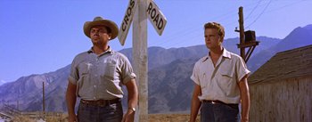 Movie still from “Bad Day at Black Rock” (1955), directed by John Sturges – A couple of men standing next to each other near a sign; Medium shot, Low angle