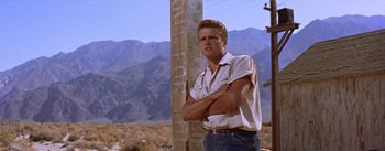 Movie still from “Bad Day at Black Rock” (1955), directed by John Sturges – A man standing next to a wooden pole in the middle of the desert; Medium shot, Low angle