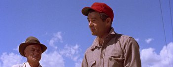 Movie still from “Bad Day at Black Rock” (1955), directed by John Sturges – An older man wearing a red hat and a plaid shirt; Medium shot, Low angle