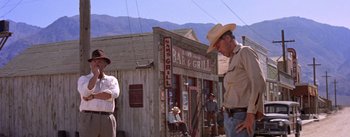 Movie still from “Bad Day at Black Rock” (1955), directed by John Sturges – A man in a cowboy hat standing in front of a bar and grill; Wide shot, Low angle