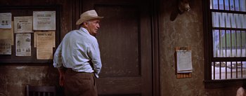 Movie still from “Bad Day at Black Rock” (1955), directed by John Sturges – An older man wearing a cowboy hat standing in front of a door; Medium shot, Low angle