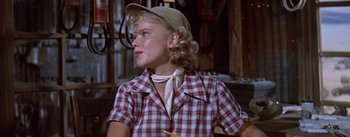 Movie still from “Bad Day at Black Rock” (1955), directed by John Sturges – A woman in a plaid shirt wearing a hat and holding a pencil; Medium shot, Over the shoulder angle