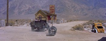 Movie still from “Bad Day at Black Rock” (1955), directed by John Sturges – An old truck driving down a dirt road next to a building; Extreme Wide shot, High angle