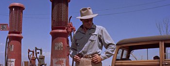 Movie still from “Bad Day at Black Rock” (1955), directed by John Sturges – A man wearing a hat standing next to a fire hydrant; Medium shot, Low angle