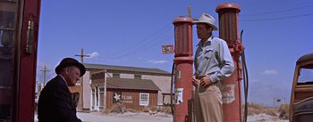 Movie still from “Bad Day at Black Rock” (1955), directed by John Sturges – A man in a cowboy hat standing next to a fire hydrant; Wide shot, Low angle