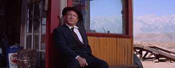 Movie still from “Bad Day at Black Rock” (1955), directed by John Sturges – An older man in a suit and hat sitting in front of a window; Medium shot, Low angle