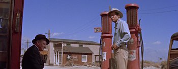 Movie still from “Bad Day at Black Rock” (1955), directed by John Sturges – A man standing next to a red fire hydrant in front of a building; Wide shot, Low angle