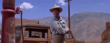 Movie still from “Bad Day at Black Rock” (1955), directed by John Sturges – A man in a hat and a tie standing in front of a truck; Medium shot, Low angle