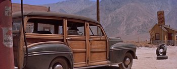Movie still from “Bad Day at Black Rock” (1955), directed by John Sturges – An old car is parked on the side of the road; Wide shot, Low angle