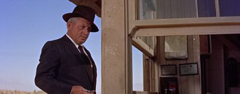Movie still from “Bad Day at Black Rock” (1955), directed by John Sturges – An older man in a suit and hat is standing next to a window; Medium shot, Low angle